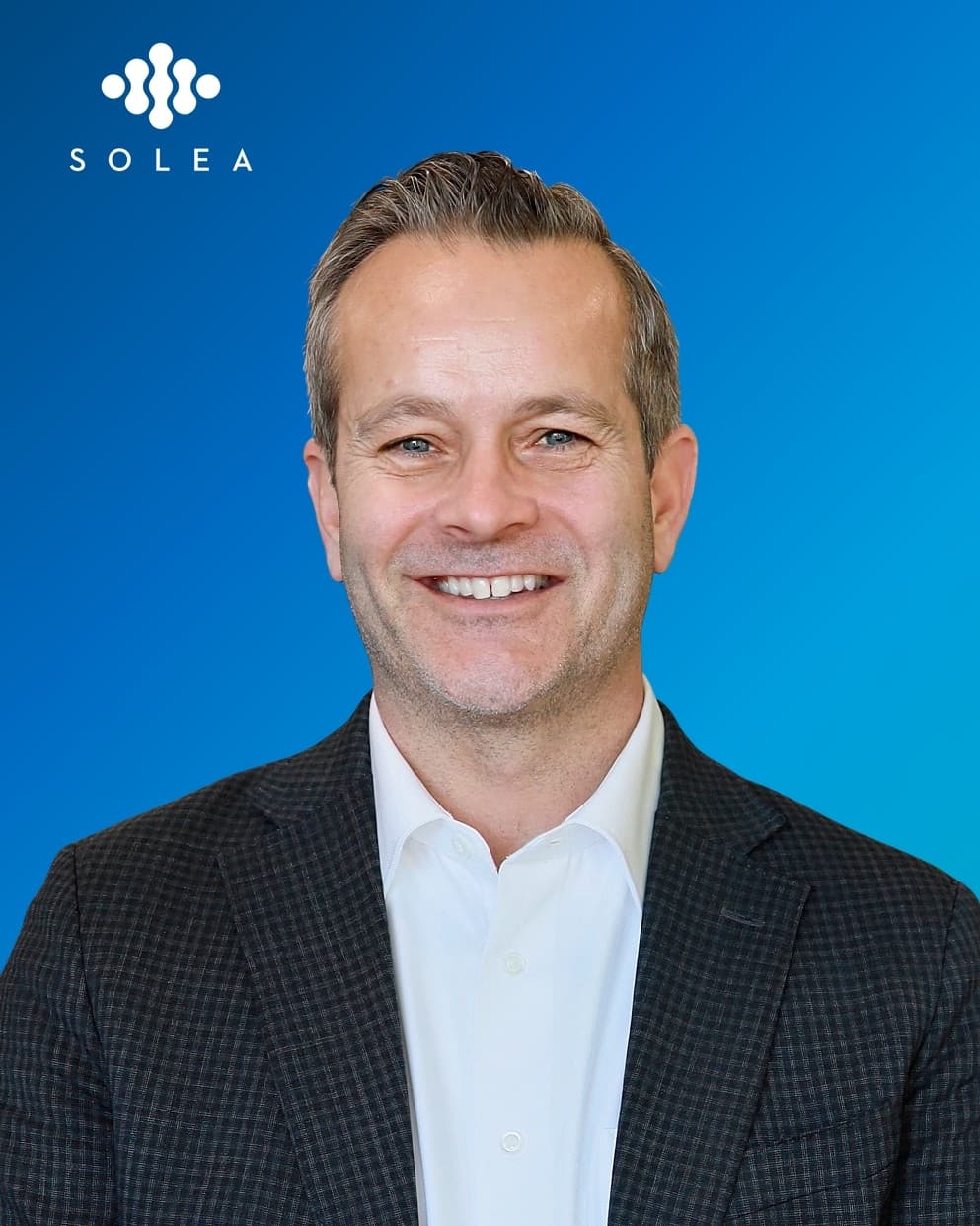 SOLEA branded headshot of a smiling man in a checkered jacket